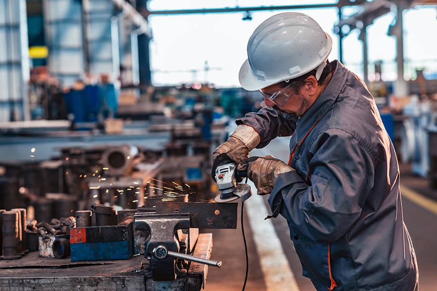 Skilled industrial worker grinding metal part. Industrial Worker Injury